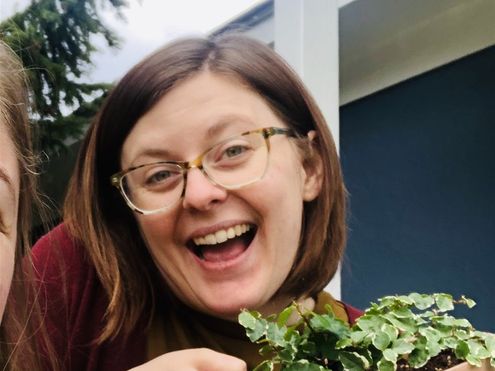 Megan smiling looking at camera holding a plant excitedly 